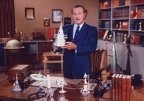 Walt Disney holds up spaceship model