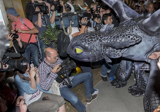 Toothless the dragon sniffs a reporter along his walk as he makes his entrance at the Cannes Film Festival