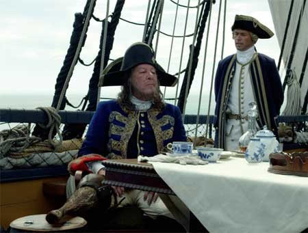 Captain Barbossa (Geoffrey Rush) enjoys a repast on the poop deck of the HMS Providence, as Groves (Greg Ellis) stands by to inform him of the crew's complaints. Copyright Disney Enterprises, Inc. All rights reserved